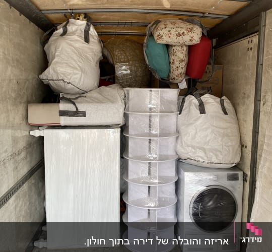 מכונת כביסה, ארגזים ושקיות בתוך משאית הובלה